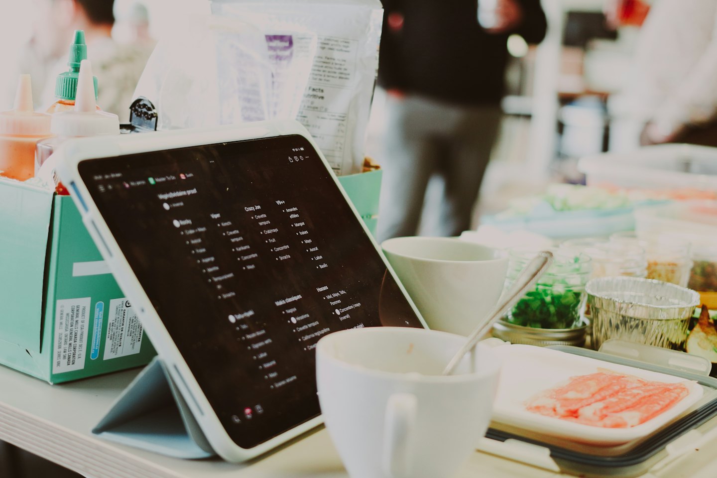 Digital menu on a tablet sits beside fresh food ingredients.