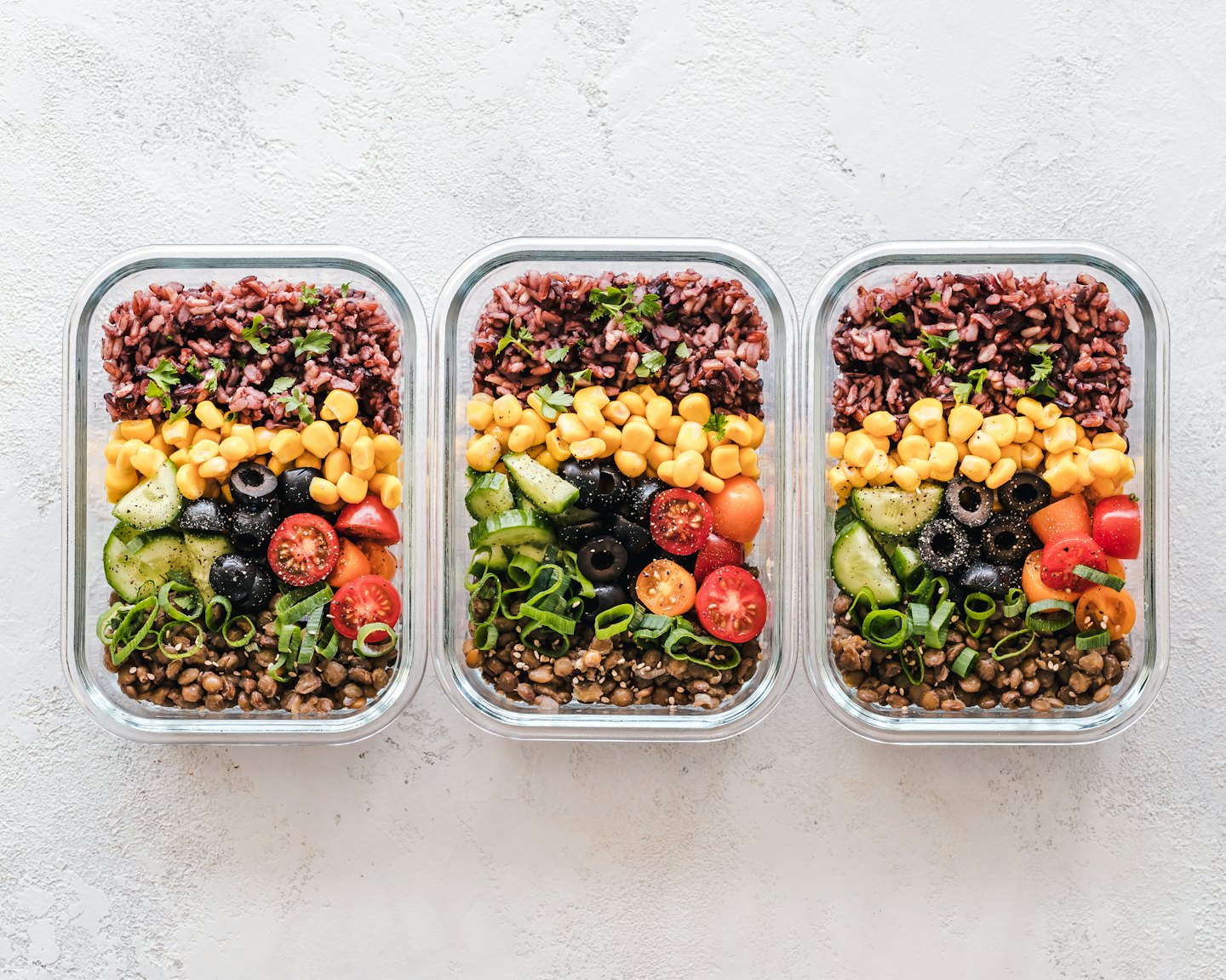 Three glass containers filled with healthy, layered ingredients.